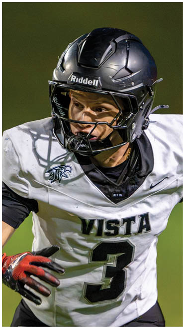 A person wearing a white sports jersey with a black undershirt is captured in close-up during an outdoor activity. Description generated by AI