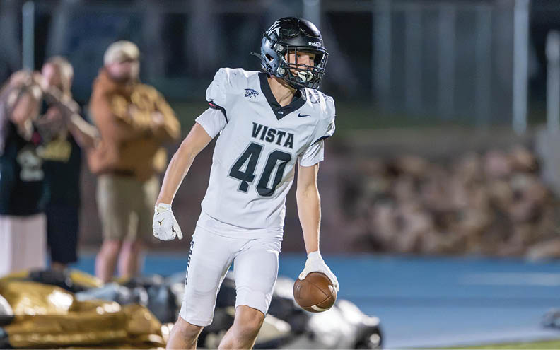 A person in a white football uniform with the number 40 and a black helmet is holding a football and running on a field. Description generated by AI