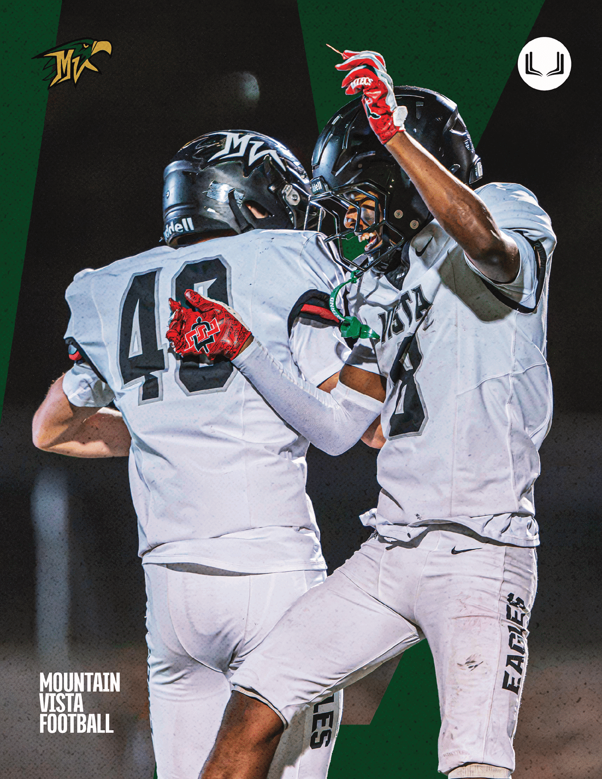 Two football players in white uniforms and black helmets celebrate on the field at night with one player raising an arm and the other pointing. Description generated by AI