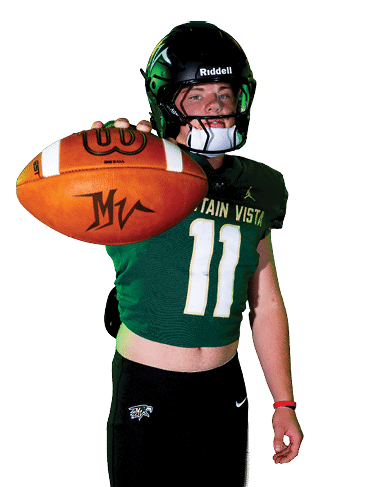 A person wearing a football helmet and uniform is holding a football extended toward the camera. Description generated by AI