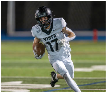 A person wearing a white football uniform with the number 17 is running on a field while holding a football. Description generated by AI