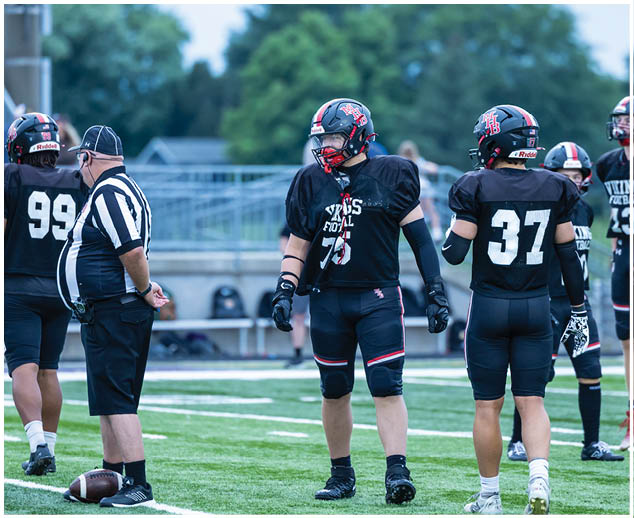 A group of football players standing on a field. Description generated by AI
