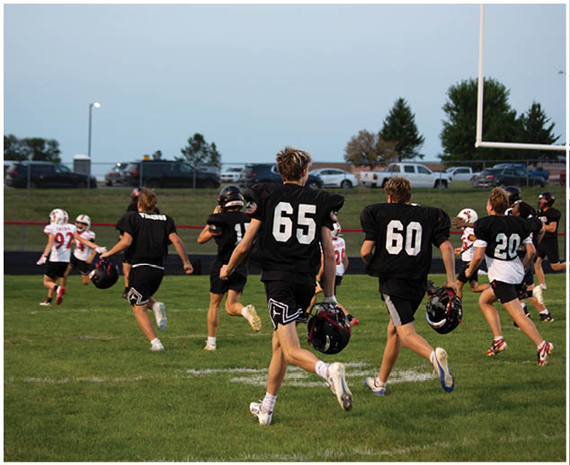 A group of football players running on a field. Description generated by AI