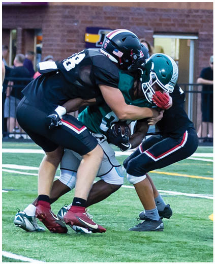 Two football players are tackling each other on the field. Description generated by AI