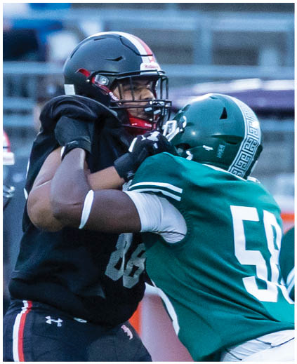 Two football players in black and green uniforms. Description generated by AI