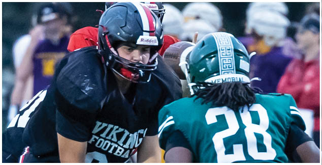 A football player in a black and red jersey is kneeling on the ground. Description generated by AI