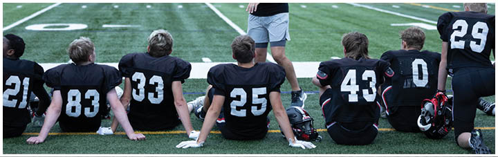 A group of football players sitting on the field. Description generated by AI