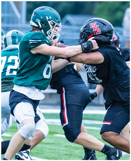 A football player in a green jersey is tackled by another player. Description generated by AI