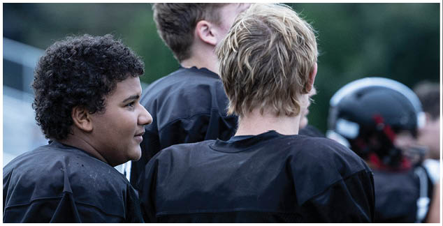 A group of football players wearing black jerseys. Description generated by AI