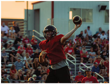 A football player in a red jersey throws a football. Description generated by AI