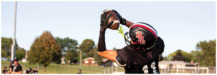 A man catching a football in a black jersey. Description generated by AI