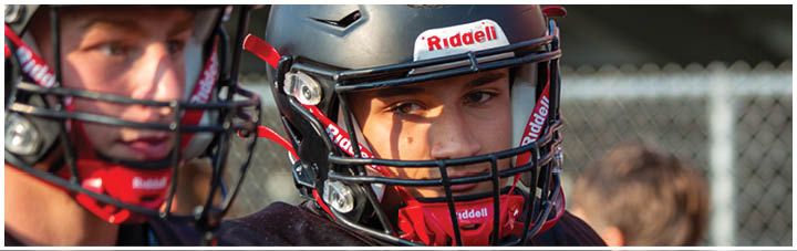 Two football players wearing helmets. Description generated by AI