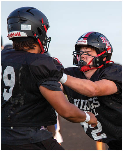Two football players are fighting on the field. Description generated by AI