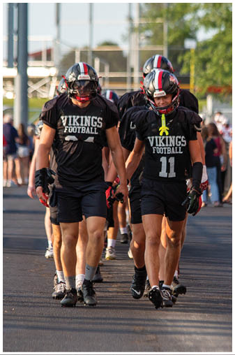 Two men wearing black jerseys with the word “Vikings" on the back. Description generated by AI
