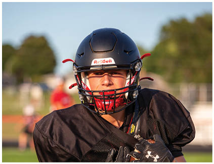 A football player wearing a black helmet and jersey. Description generated by AI