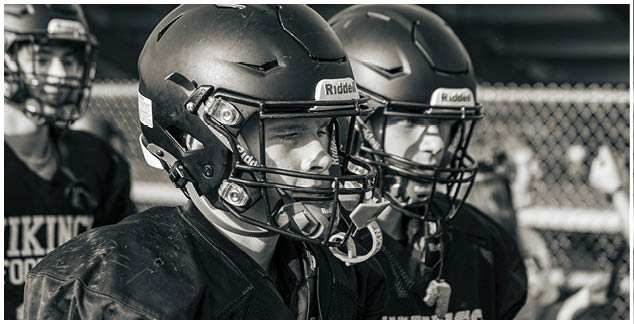 Two football players wearing black helmets. Description generated by AI
