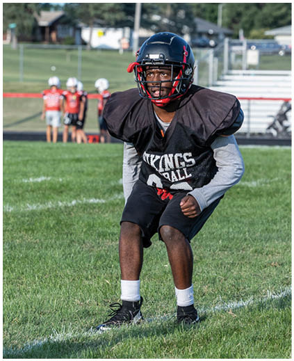 A young boy wearing a black and red football jersey. Description generated by AI