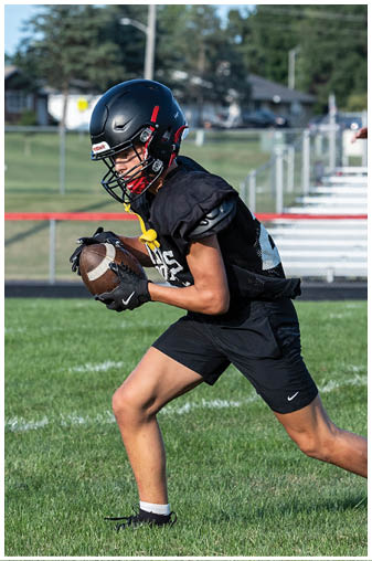 A football player in a black jersey with the number 12 on it. Description generated by AI