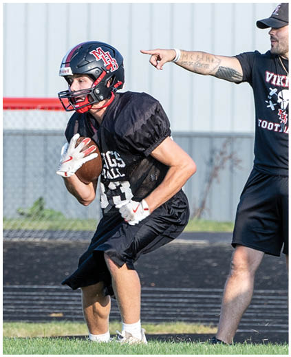 A football player in a black jersey with a red helmet. Description generated by AI
