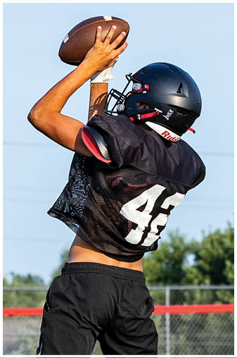 A man catching a football in a black and red jersey. Description generated by AI