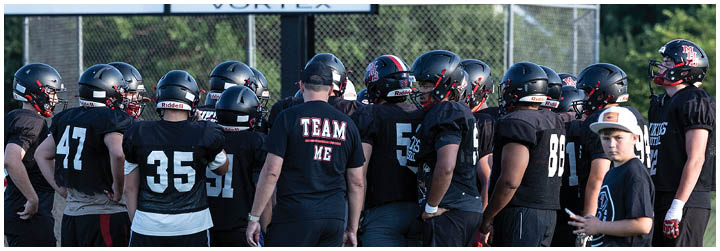 A group of football players in black uniforms. Description generated by AI