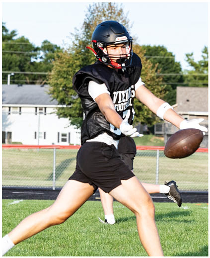 A man in a black jersey catching a football. Description generated by AI