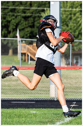 A boy running in a field with a football in his hand. Description generated by AI