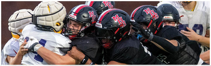 A group of football players in black and red uniforms are playing on a field. Description generated by AI
