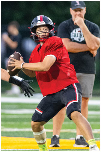 A football player in a red jersey is holding a football. Description generated by AI