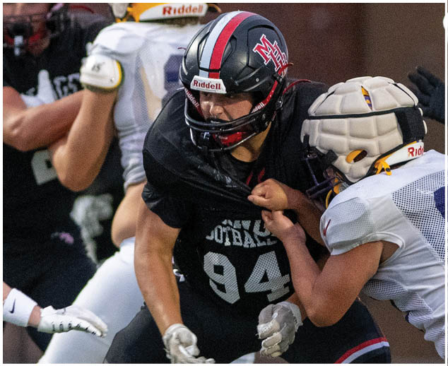 A football player wearing a black jersey with the number 94 on it. Description generated by AI