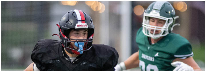 A football player wearing a black jersey with the number 5 on it. Description generated by AI