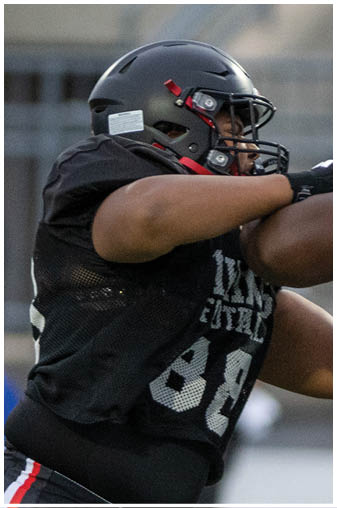 Two football players in green and black uniforms. Description generated by AI