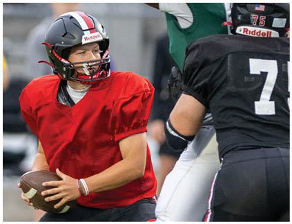 A football player in a red jersey is holding a football. Description generated by AI