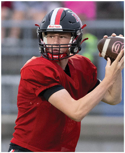 A football player wearing a red jersey and black shorts. Description generated by AI