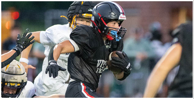 A football player in a black jersey running on the field. Description generated by AI