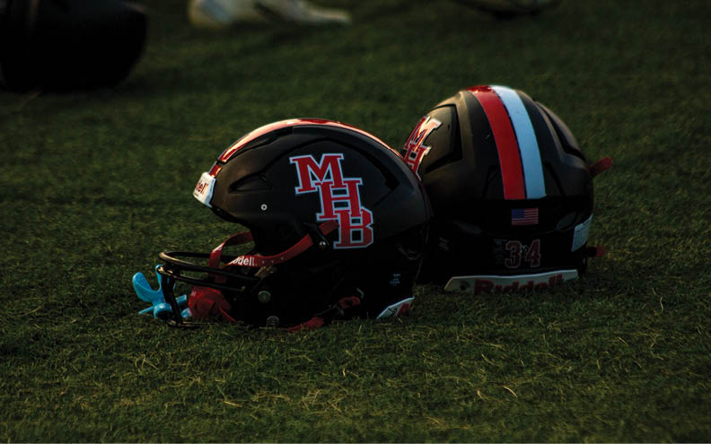 Two football helmets are on the ground. Description generated by AI