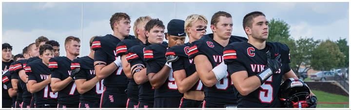 A group of football players wearing black jerseys and white pants. Description generated by AI