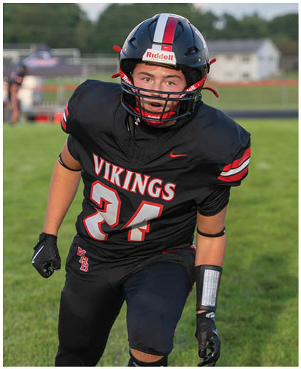 A football player wearing a black and red jersey with the number 24 on it. Description generated by AI