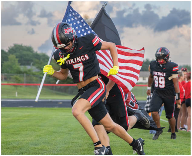 A football player running with a flag in his hand. Description generated by AI