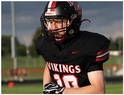 A football player wearing a black jersey with the word Vikings on it. Description generated by AI