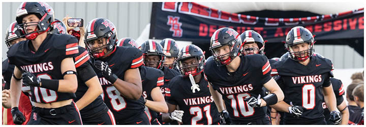 A group of football players wearing black jerseys with the word Vikings on the front. Description generated by AI