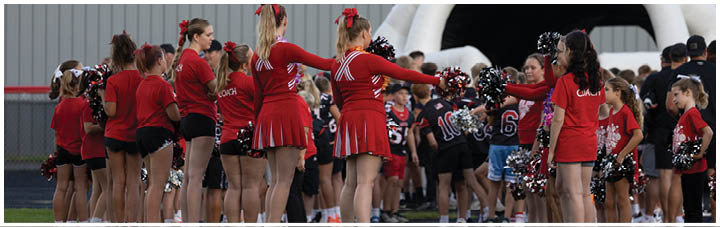 A group of cheerleaders in red and white uniforms. Description generated by AI