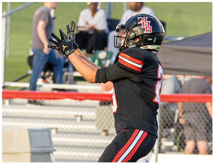 A football player catching a ball on a field. Description generated by AI