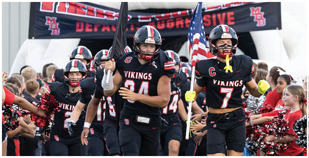 A group of football players in black jerseys with the word Vikings on them. Description generated by AI