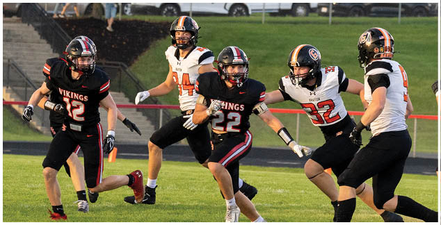 A group of football players running on a field. Description generated by AI