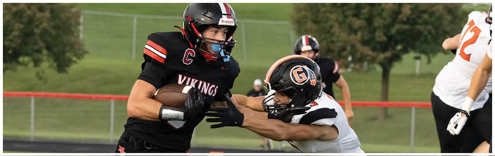 A football player wearing a black jersey with the number 12 on it. Description generated by AI