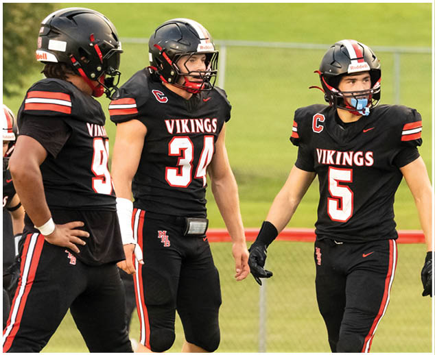 A group of football players wearing black jerseys with the word Vikings on them. Description generated by AI
