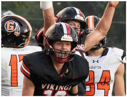 A football player wearing a black helmet and jersey with the number 16. Description generated by AI