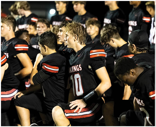 A group of football players wearing black jerseys with the number 10. Description generated by AI