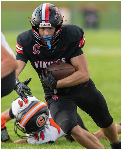 A football player in a black jersey with the number 44 on it is running with the ball. Description generated by AI